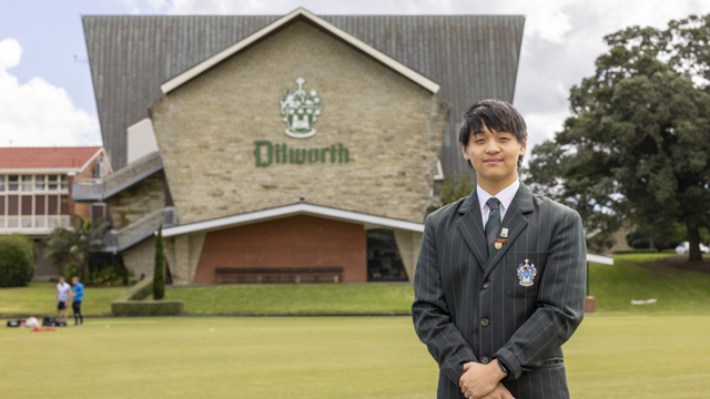 Dilworth Head Prefect standing on field infront of main Senior Campus building