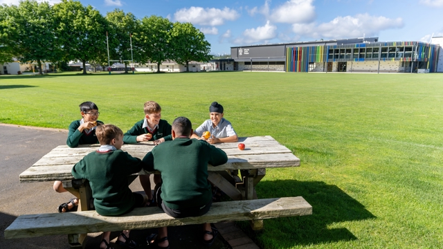 boys sitting at a picnic table eating fruit 