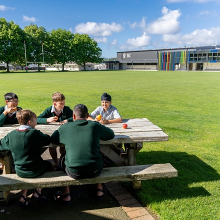 boys sitting at a picnic table eating fruit 