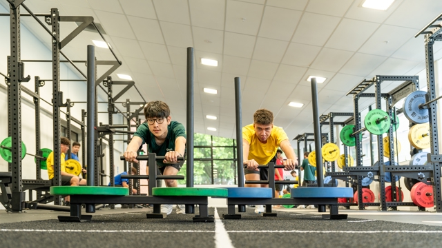 two boys pushing weights across the gym floor 
