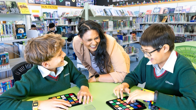 boys and students playing a board game in the library 