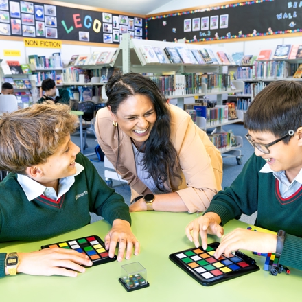 boys and students playing a board game in the library 